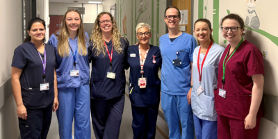 Seven healthcare professionals standing in a hospital corridor.