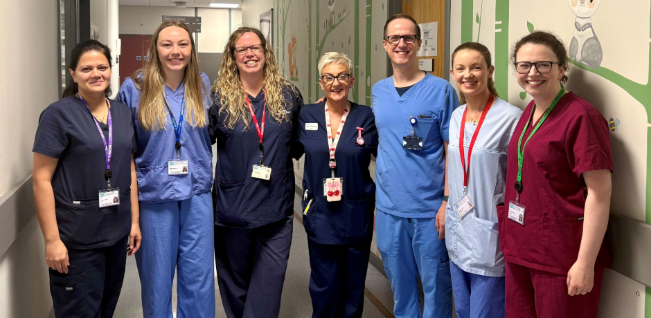 Seven healthcare professionals standing in a hospital corridor.