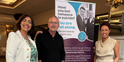 Group of three staff standing in front of bereaved by suicide banner.