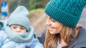 A woman smiling at a baby who is wrapped up in warm clothes.