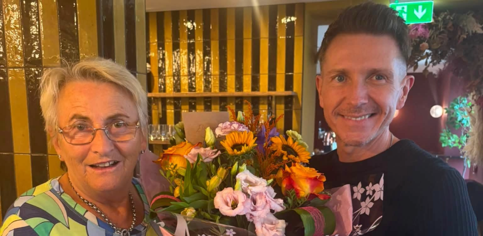 A woman receives a large bouquet of flowers from a man.