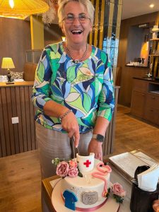 A woman cuts a celebratory cake, with medical themed decorations on it.