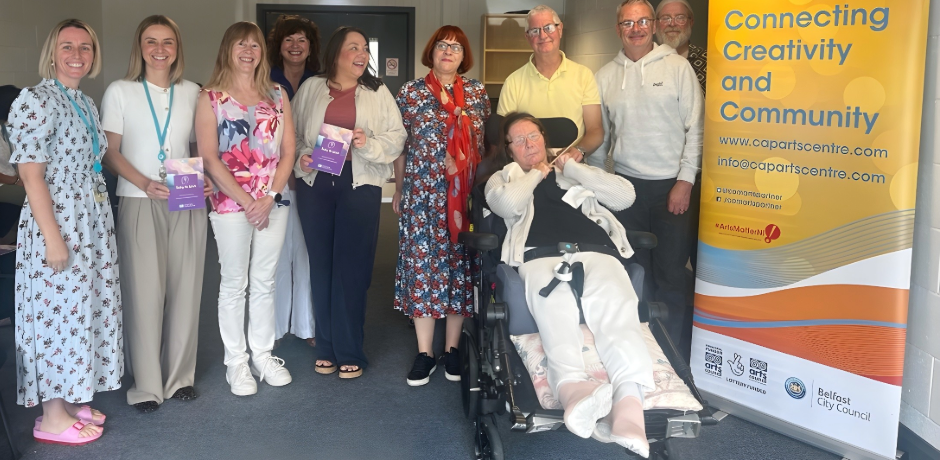 A group of people beside a pop-up banner for Community Arts Partnership.