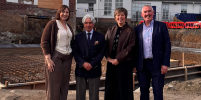 Four people standing together with a building site behind them.