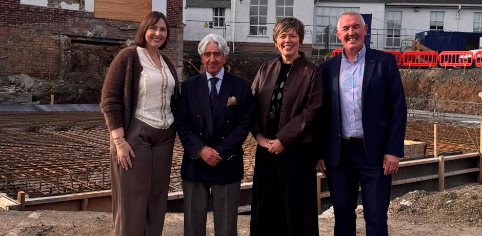 Four people standing together with a building site behind them.