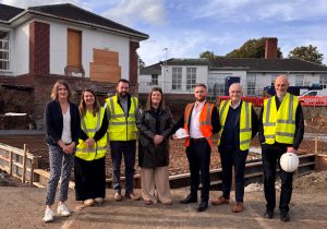 A group of people, some wearing high viz and holding hard hats, standing at the site of building works at Robinson Memorial Hospital.