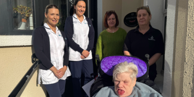 A group of women standing with a service user in a wheelchair.