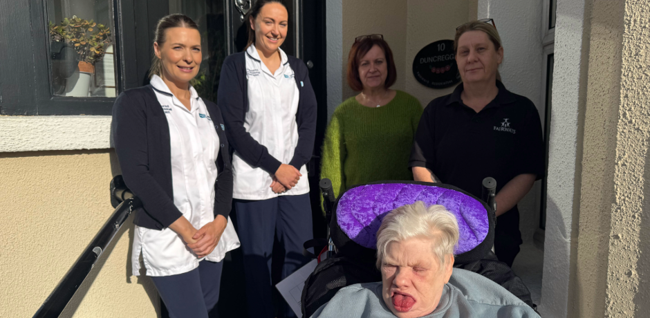 A group of women standing with a service user in a wheelchair.