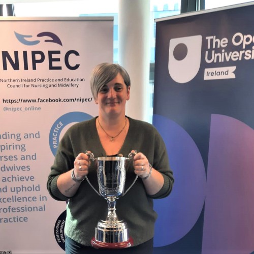 Northern Trust nurse Shelley Taylor pictured with her Student Excellence award. Shelley Taylor holding a trophy with pop-up banners behind.