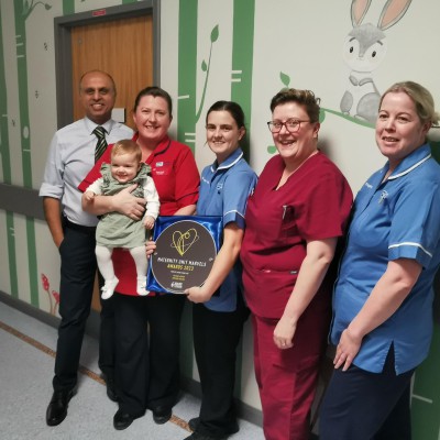 Consultant Paediatrician, Dr Sanjeev Bali, Sister Karen Devlin with baby Freya, Staff Nurse Megan Watson, Enhanced Neonatal Nurse Practioner Angela McCoy and Staff Nurse Lyndsey Wilgaus pictured with the Maternity Unit Marvel (MUM) award. Neonatal Unit staff members with a baby and the MUM award.
